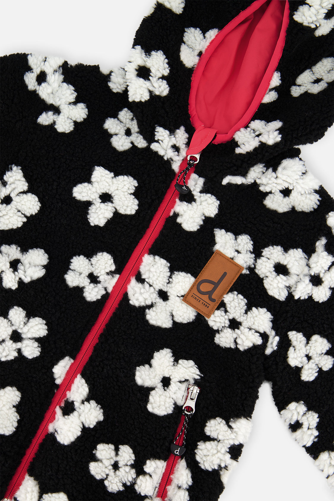 Close-up of the white flowers on the black sherpa, the pink zipper and the brand label
