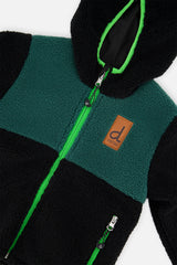 Close-up of the dark green chest panel, bright green zipper and brand label on the sherpa side