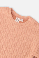 Close-up of the quilted pattern and shoulder buttons on the peach-pink Deux par Deux sweatshirt