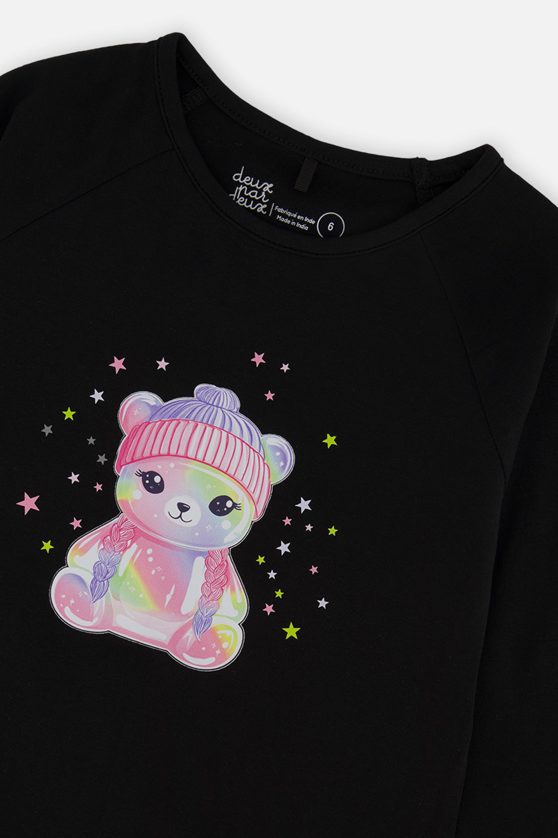 Close-up of the rainbow teddy bear in a pink hat with stars on the black tee
