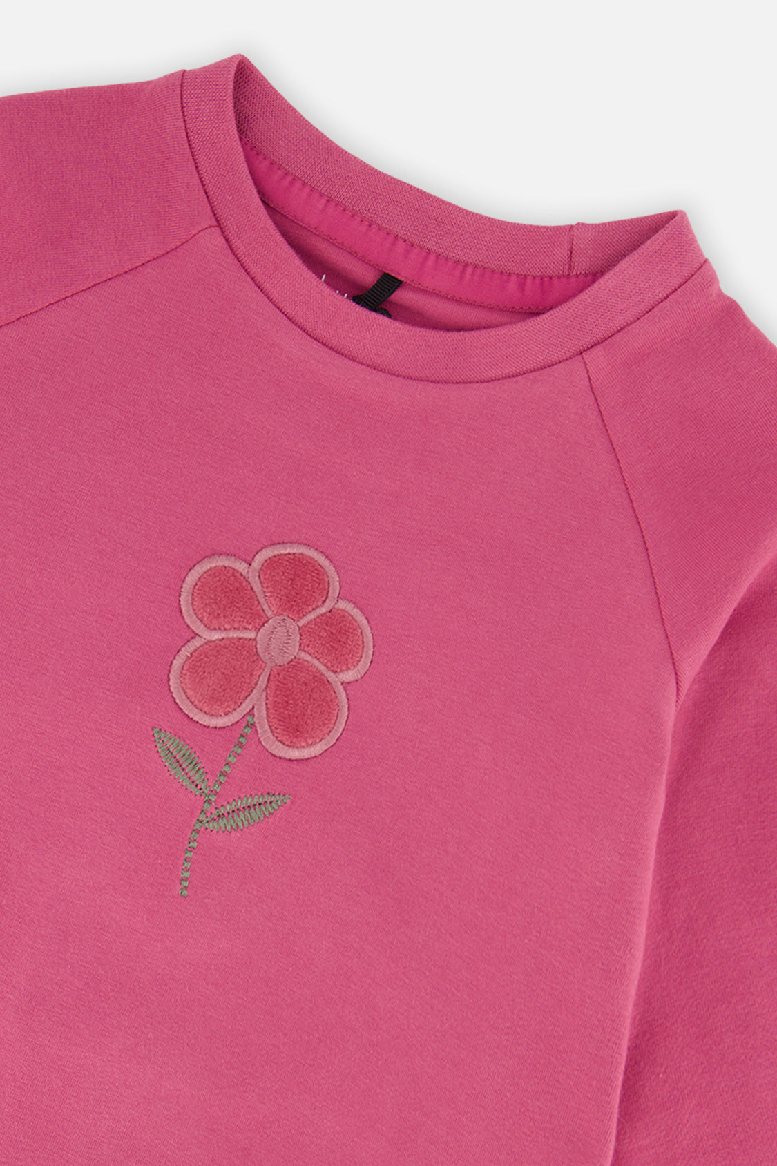 Close-up of the textured flower appliqué near the crew neckline