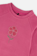 Close-up of the textured flower appliqué near the crew neckline