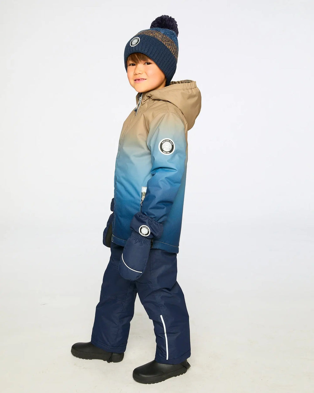Lifestyle photo of child wearing Deux par Deux navy blue snowsuit outdoors