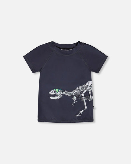 Front flat lay of Deux par Deux boy short sleeve kids rashguard in black with dinosaur skeleton print