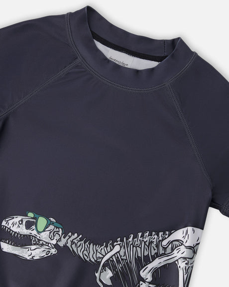 Close-up of neckline and dinosaur skeleton in sunglasses graphic on black rashguard top