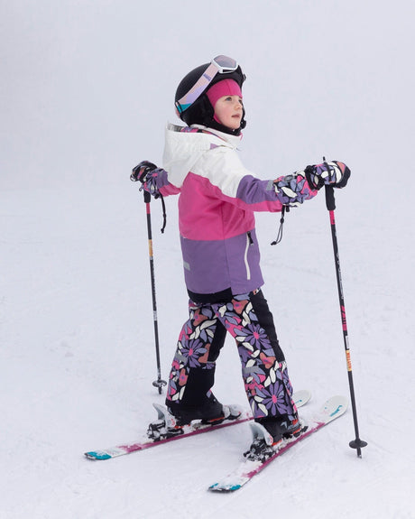 Side view of child skiing in Teknik snowsuit with helmet-friendly hood and waterproof zippers