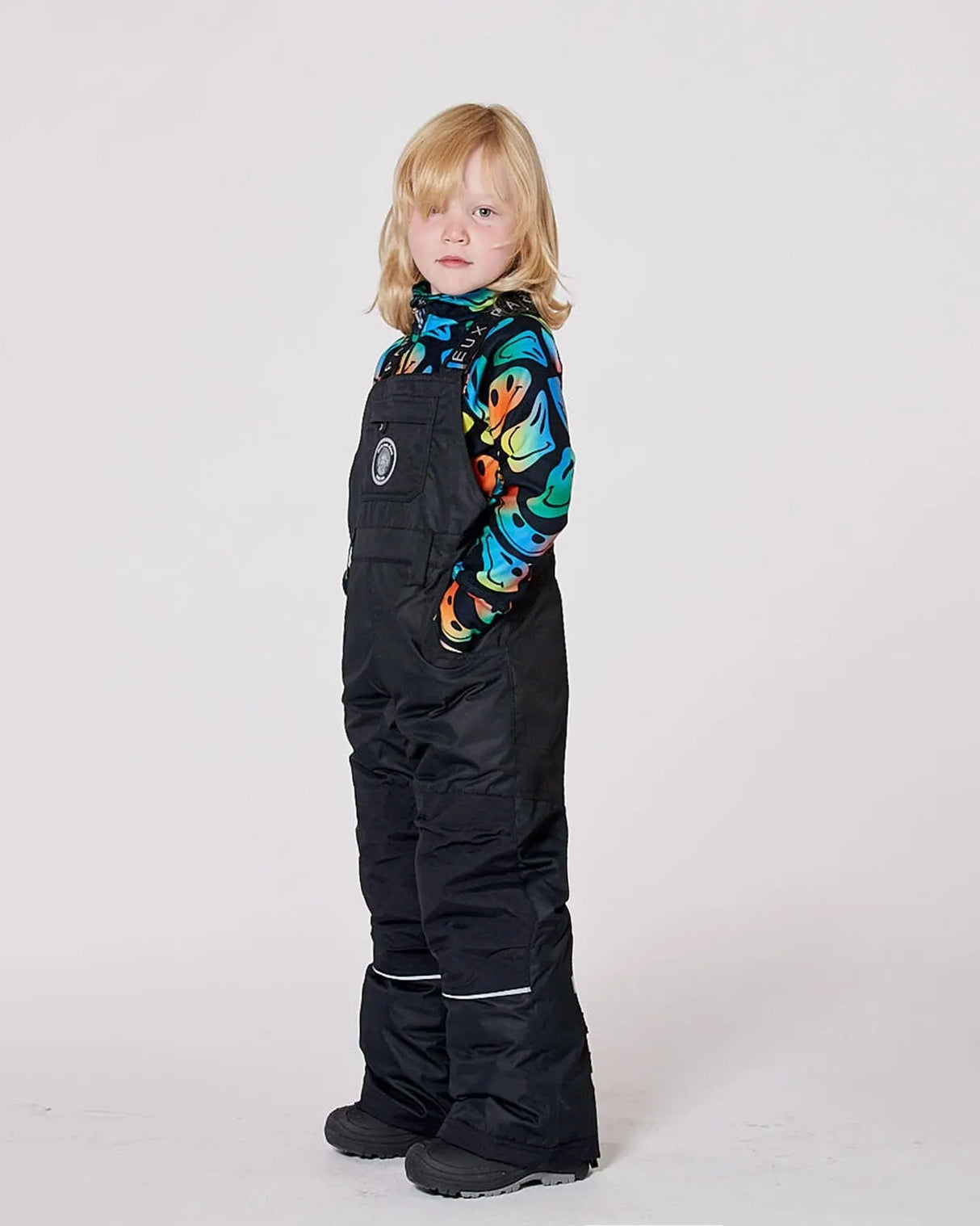 Boy wearing black insulated snow bib overalls with suspenders.