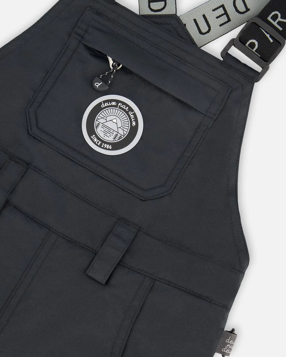 Closeup of Cordura® reinforced black bib overall with logo patch.