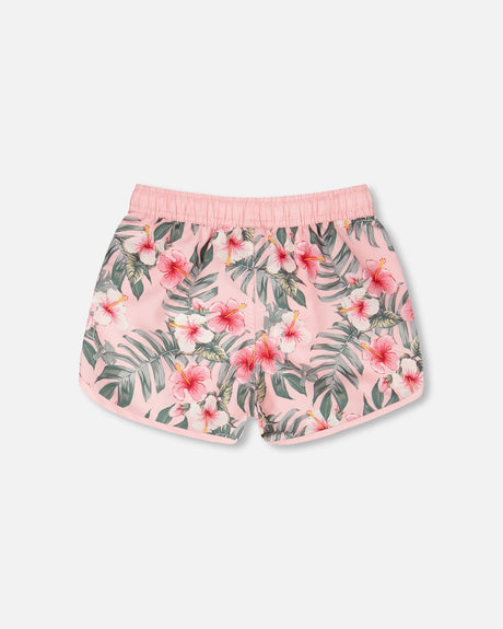 Side view of pink hibiscus boardshorts for girls showing curved hem and waistband