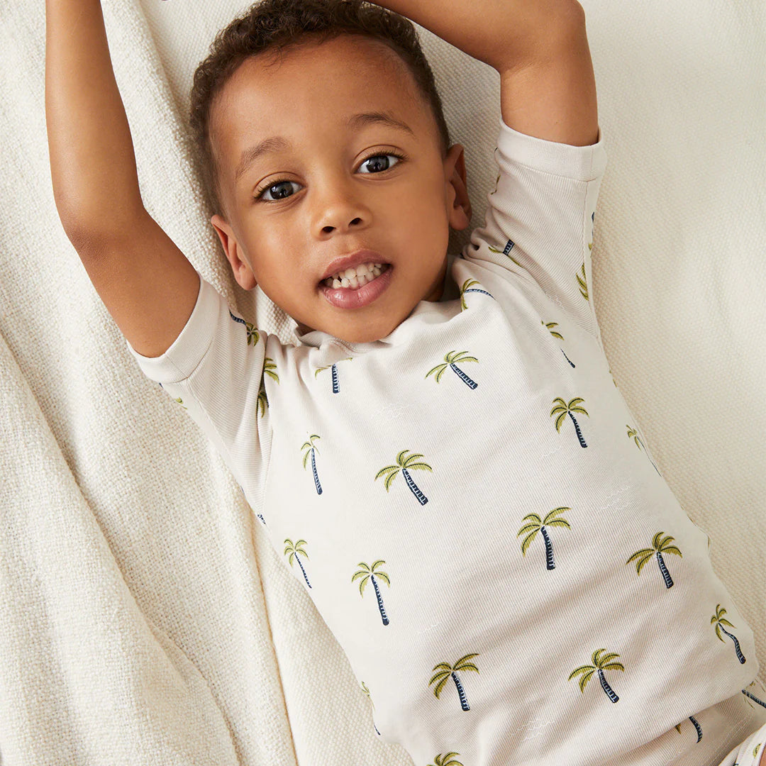 Toddler wearing coordinating palm tree print sleeper by Petit Lem