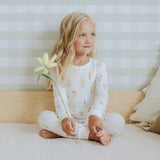 Toddler wearing off-white daffodil floral organic cotton pajama set by Petit Lem