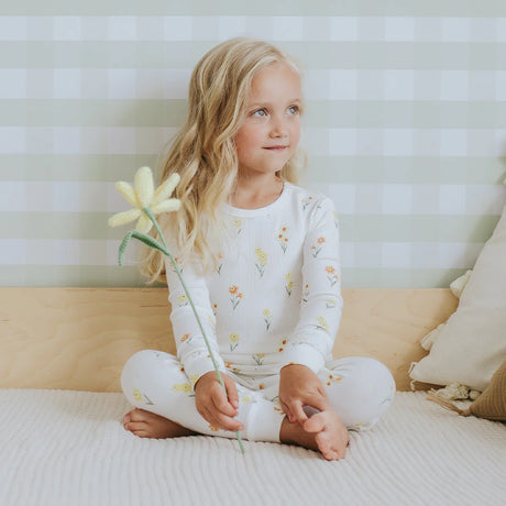 Toddler wearing off-white daffodil floral organic cotton pajama set by Petit Lem