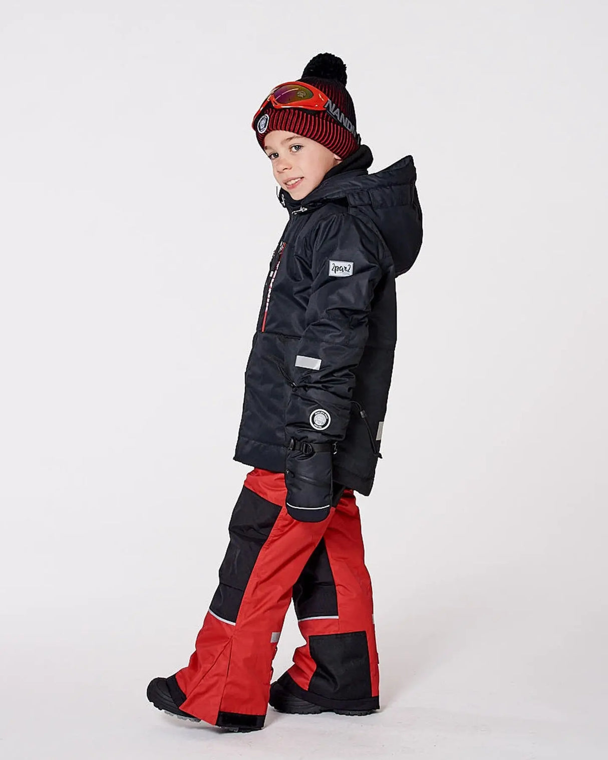Boy wearing red TEKNIK snowsuit set in winter scene
