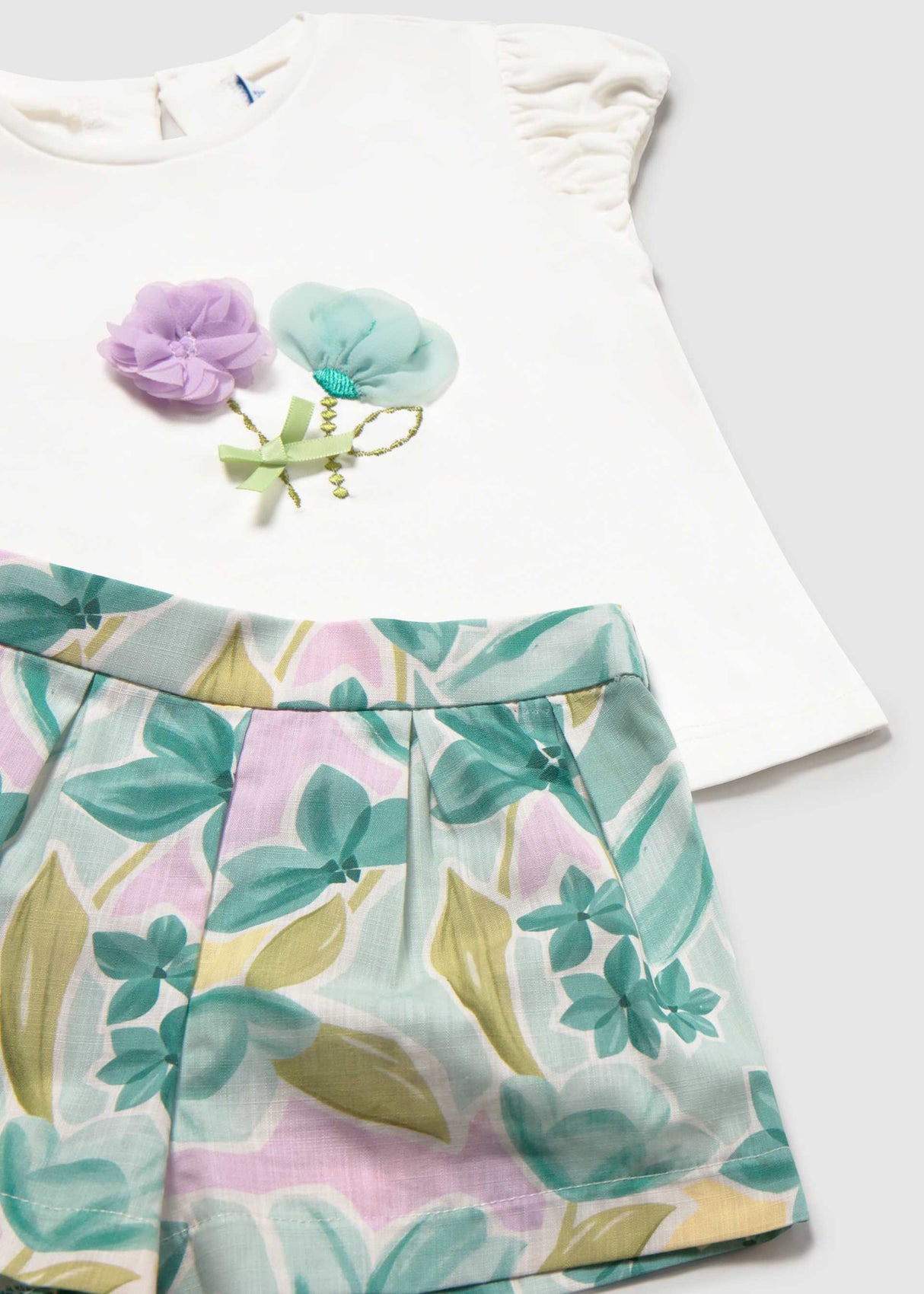 Closeup of Mayoral baby outfit showing floral graphic tee and colorful printed shorts.