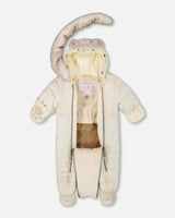 Lifestyle photo of a baby wearing the White Asparagus Layette snowsuit outdoors