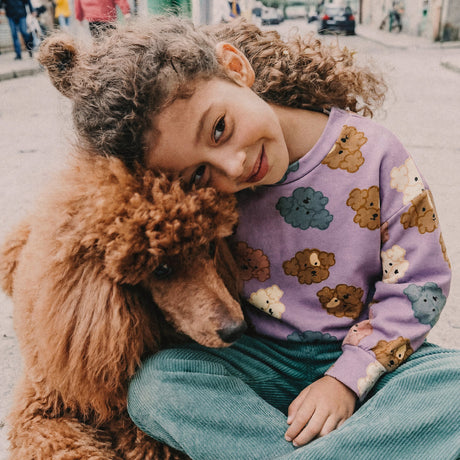 Girl in a Deux par Deux purple poodle print sweatshirt hugging a poodle