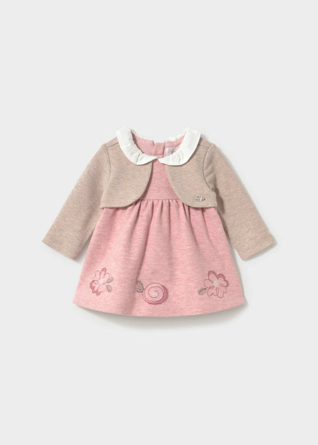 Front view of the powder pink Mayoral baby dress with a beige cardigan layer and embroidered hem flowers