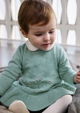 Baby wearing the sage green knit dress with cream Peter Pan collar