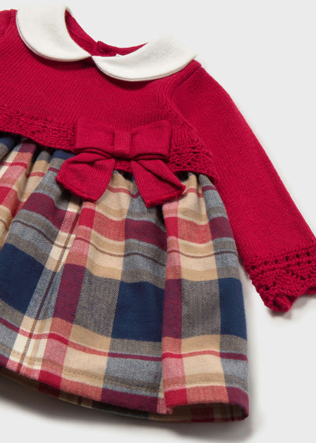 Close-up of Mayoral newborn girl knit dress showing white collar, red bodice, plaid skirt, and bow.